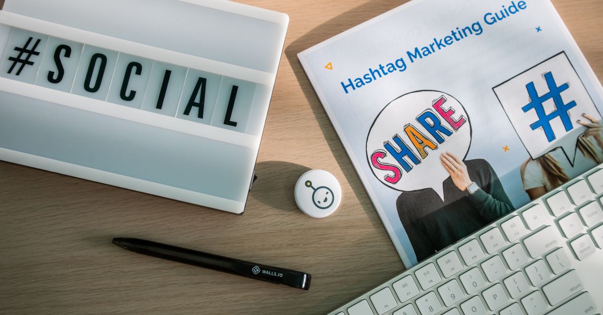 A marketing professional working on social media content at a desk with a laptop and phone