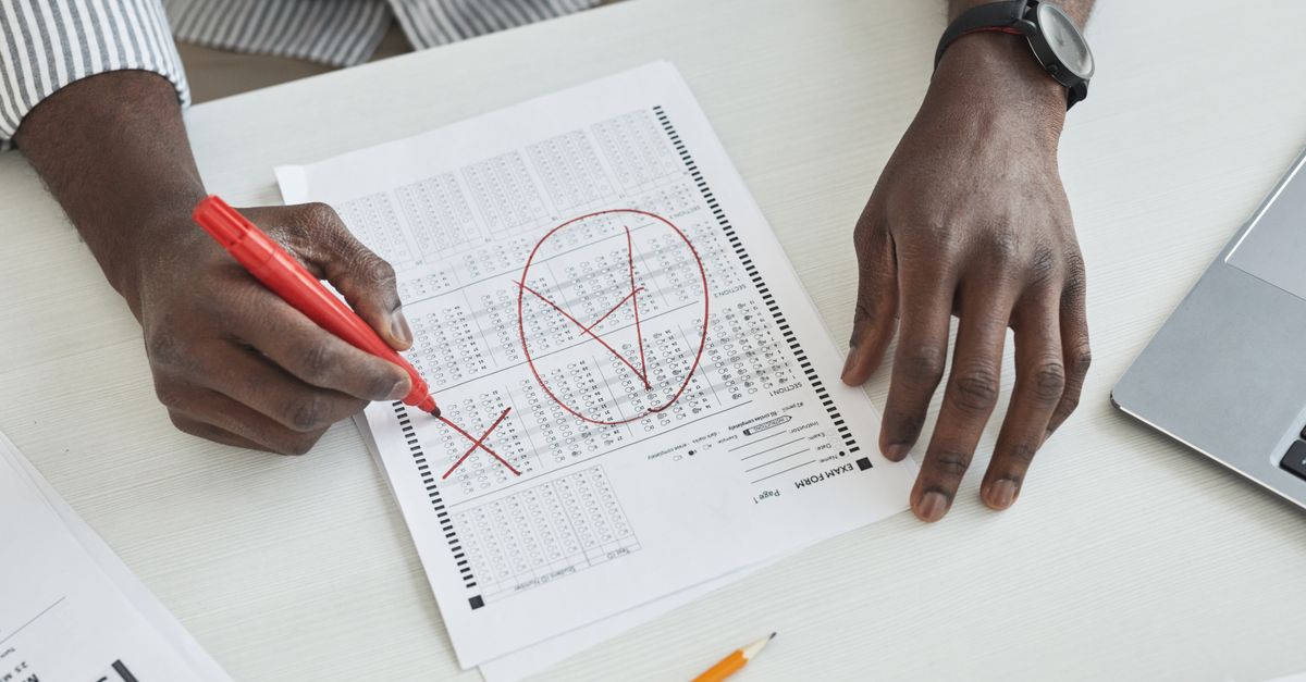 Academic reviewing written exam papers at a desk