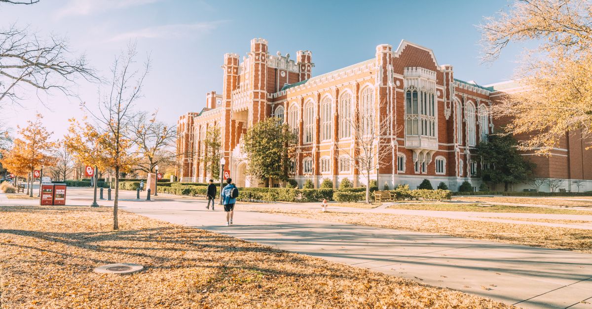 A red brick university building with students walking across the campus